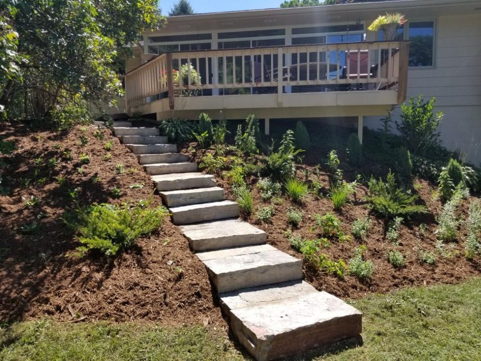 <strong>After</strong>: Our clients never have to mow this hill again. They traded their hillside lawn for a butterfly garden filled with spreading native plants and stone staircase that creates safe passage down to the backyard and patio.