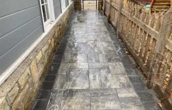 Newly installed pavers leading between a home and fence