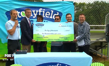 An oversized check being presented in front of Fox 9