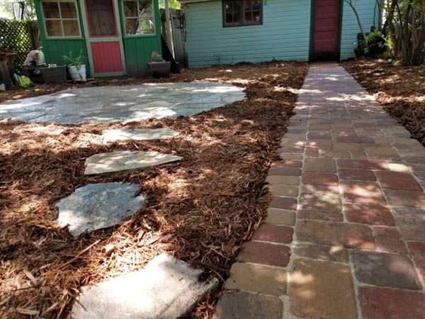 Brick paver walkway that leads through a mulch garden