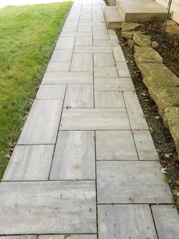 Paver walkway along a home and its lawn