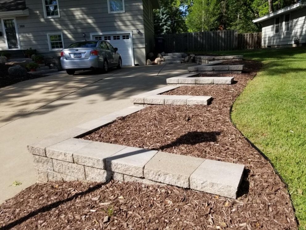 Multi-tiered retaining wall and garden near a driveway