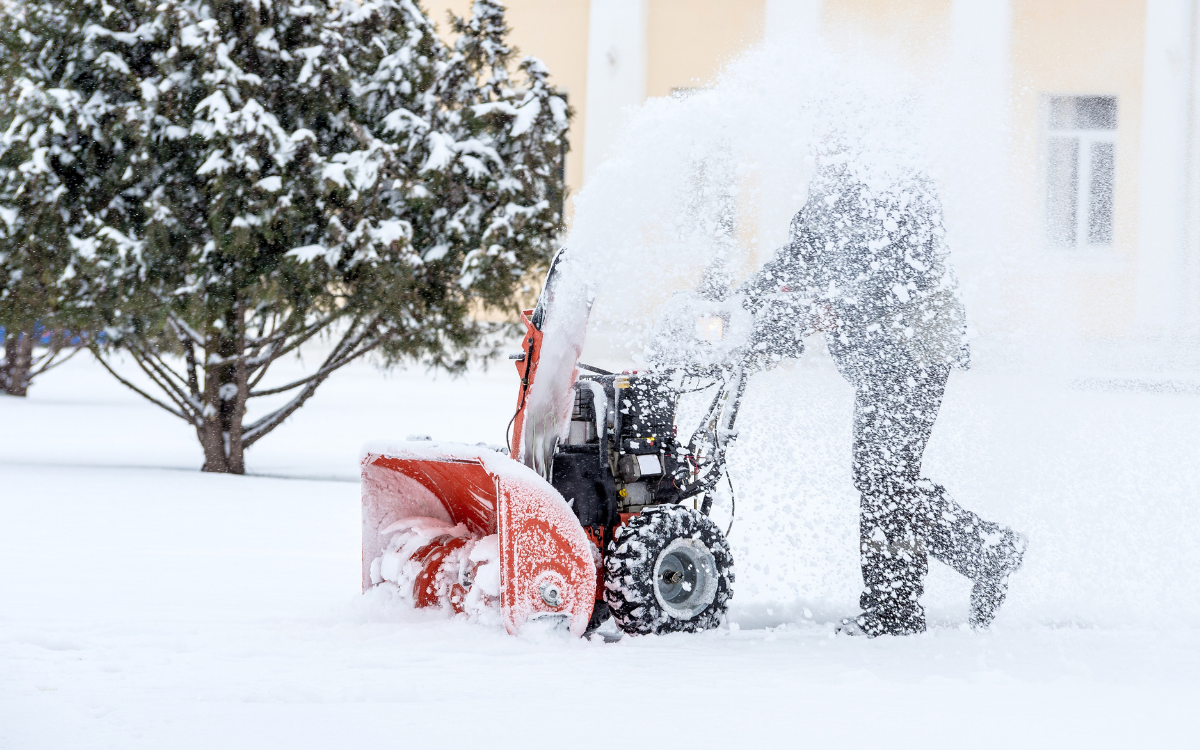 Minneapolis man using a snow blower on a parking lot