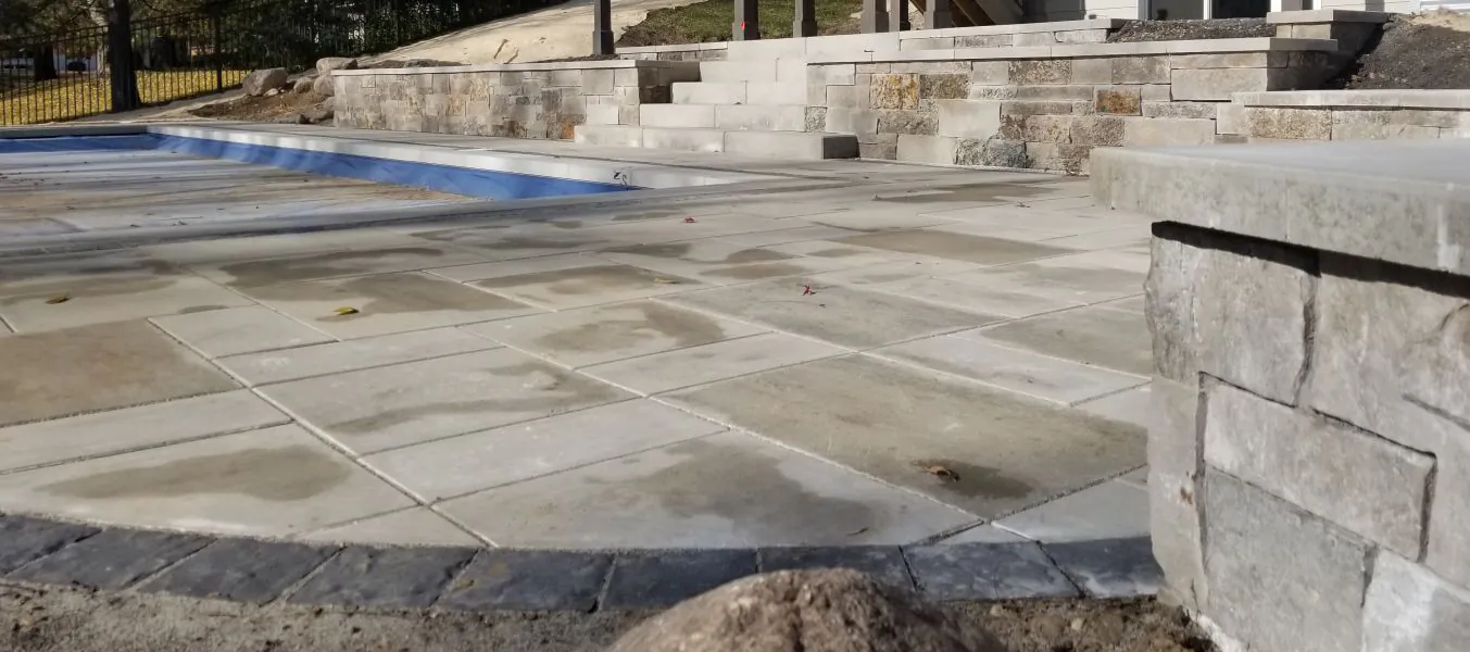 Natural stone patio beside a pool with a tiered stone retaining wall and steps in a Bloomington, MN backyard