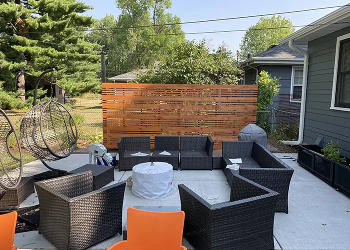 Outdoor lounge with wicker sofas, orange accent chairs and a cedar privacy screen on a patio in Edina, MN